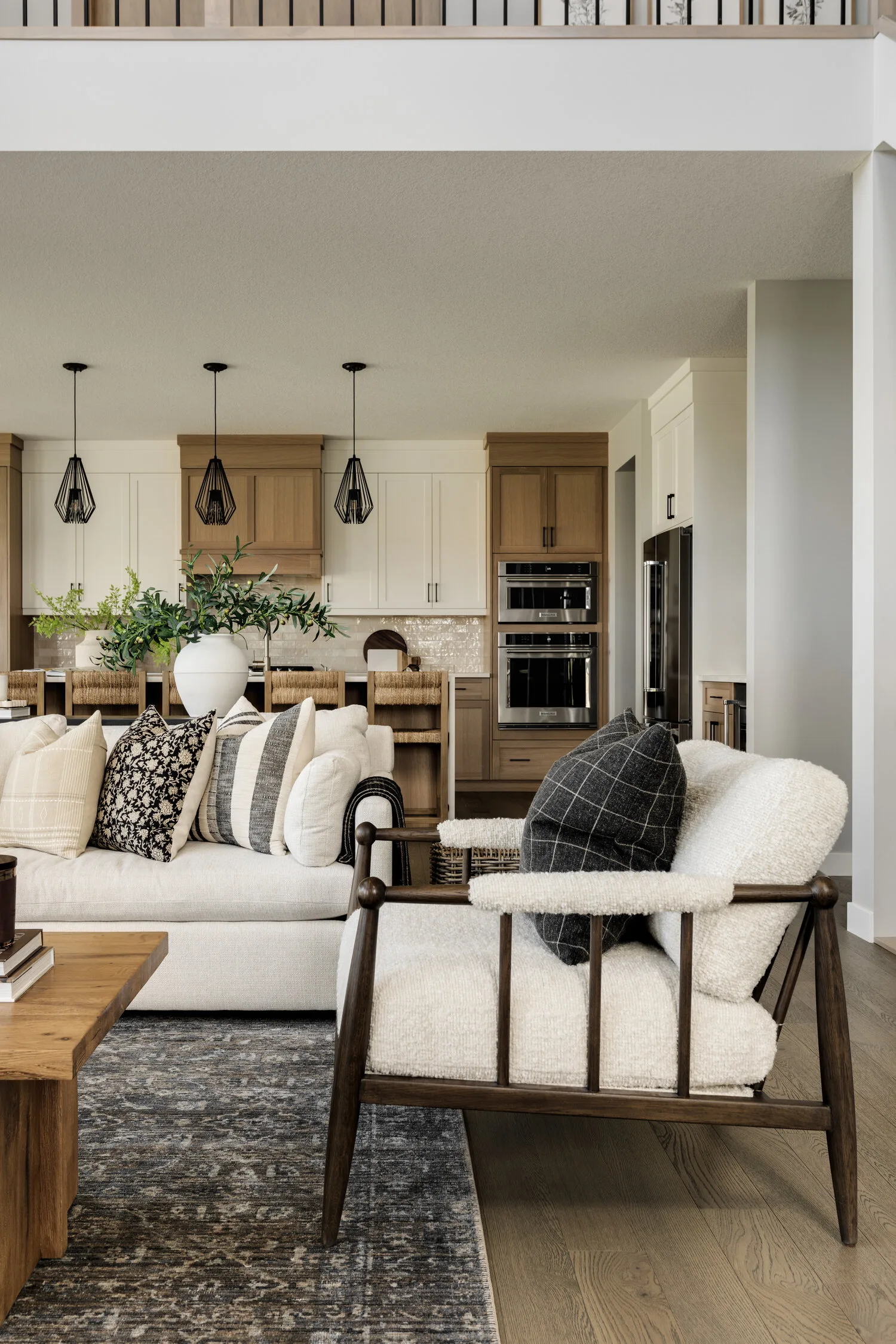 Open living room and kitchen with layered furnishings, wood cabinetry, and black accents